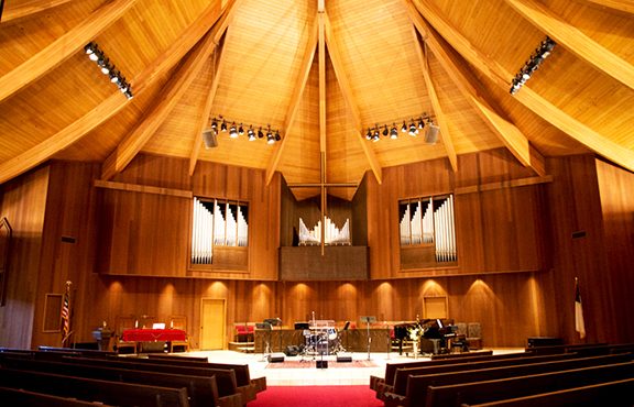 Wood-paneled sanctuary with organ pipes and a vaulted wooden ceiling